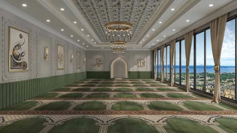 Rooftop prayer hall with green carpet and tall windows over the city